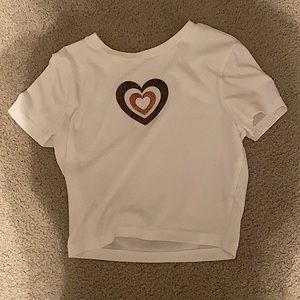 A white crop top with a brown glittered heart in the center